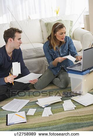 Stock Photo - USA, New Jersey, Jersey City, Portrait of young couple doing paperwork at home. Fotosearch