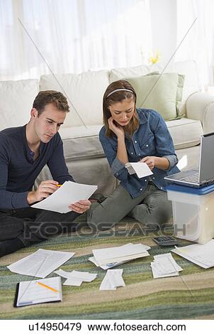 Stock Photo - USA, New Jersey, Jersey City, Portrait of young couple doing paperwork at home. Fotosearch