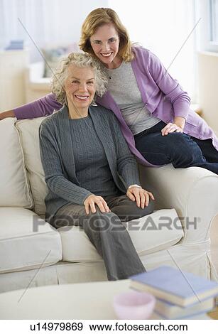 Stock Photo - USA, New Jersey, Jersey City, Portrait of mother and daughter smiling on sofa. Fotosearch