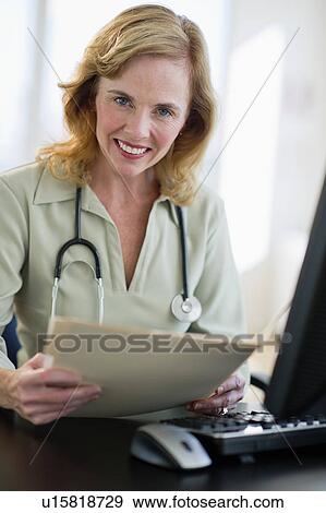 USA, New Jersey, Jersey City, Portrait of female doctor holding medical record in office View Large Photo Image Stock Photo - USA, New Jersey, Jersey City, Portrait of female doctor holding medical record in office. Fotosearch