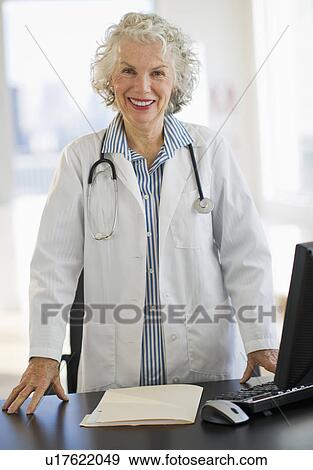 Stock Photo - USA, New Jersey, Jersey City, Portrait of senior female doctor in office. Fotosearch