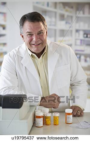 Stock Photo - USA, New Jersey, Jersey City, Portrait of pharmacist selling medication in pharmacy. Fotosearch