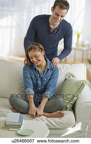 Stock Photo - USA, New Jersey, Jersey City, Portrait of young couple relaxing on sofa. Fotosearch