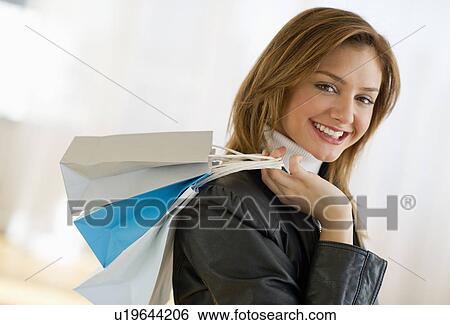 Stock Photograph - USA, New Jersey, Jersey City, Portrait of young woman with shopping bags. Fotosearch