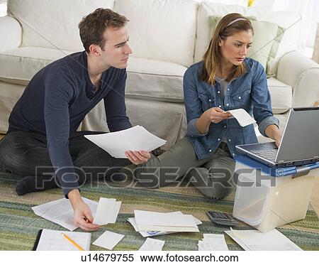 Stock Photography - USA, New Jersey, Jersey City, Portrait of young couple doing paperwork at home. Fotosearch