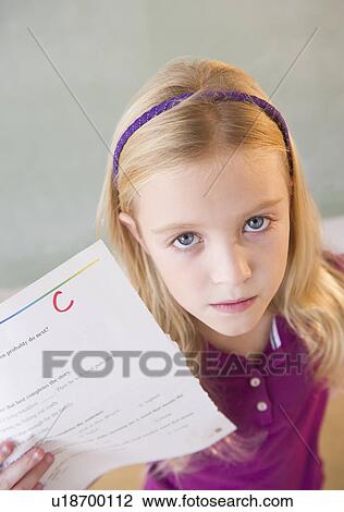 Stock Image - USA, New Jersey, Jersey City, Sad schoolgirl (8-9) showing test results with C-grade. Fotosearch