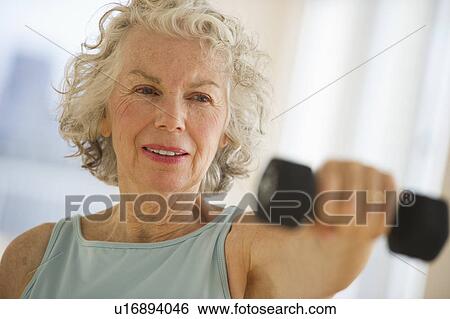 Stock Photograph - USA, New Jersey, Jersey City, Senior woman using hand weights at gym. Fotosearch