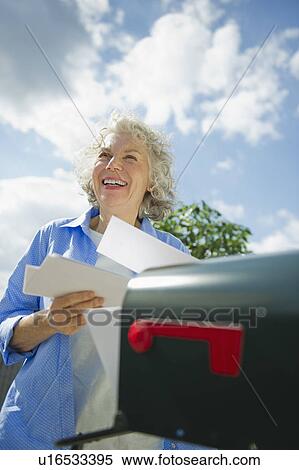 Stock Photography - USA, New Jersey, Jersey City, Senior woman checking mail at mailbox. Fotosearch