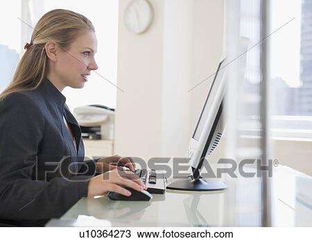 Stock Image - USA, New Jersey, Jersey City, Businesswoman working on computer. Fotosearch