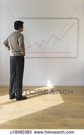 Stock Image - USA, New Jersey, Jersey City, Businessman observing line graph. Fotosearch