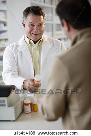 Stock Photo - USA, New Jersey, Jersey City, Pharmacist selling medication in pharmacy. Fotosearch