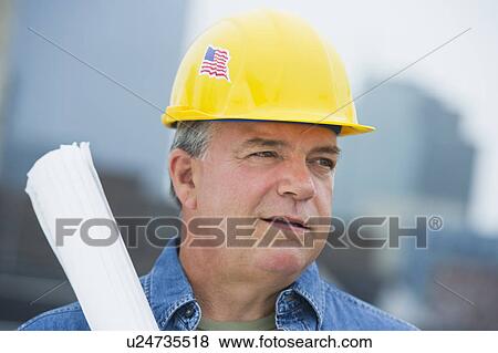 Stock Photo - USA, New Jersey, Jersey City, Construction worker holding blueprints on construction site. Fotosearch