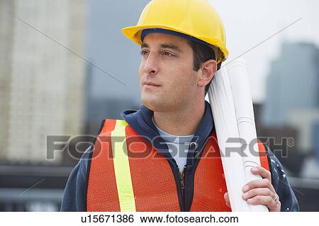 Stock Photograph - USA, New Jersey, Jersey City, Construction worker holding blueprints on construction site. Fotosearch