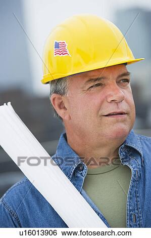 USA, New Jersey, Jersey City, Construction worker holding blueprints on construction site View Large Photo Image Stock Photograph - USA, New Jersey, Jersey City, Construction worker holding blueprints on construction site. Fotosearch