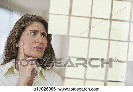 Stock Photograph - USA, New Jersey, Jersey City, Businesswoman observing adhesive notes on window. Fotosearch