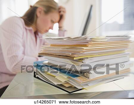 Stock Image - USA, New Jersey, Jersey City, Stressed young businesswoman doing paperwork. Fotosearch