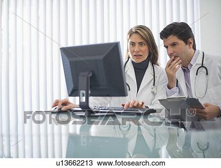 Stock Image - USA, New Jersey, Jersey City, Two doctors using computer in office. Fotosearch