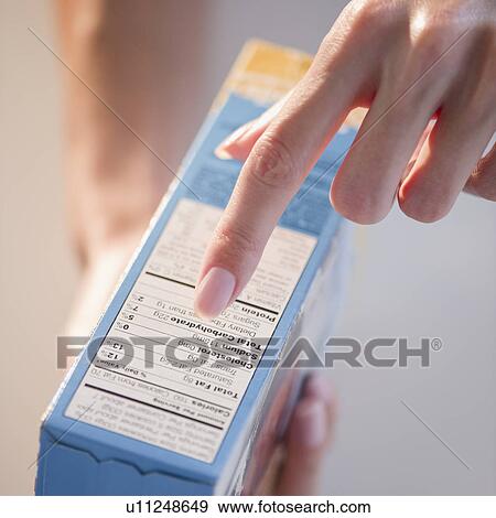 Stock Photo - USA, New Jersey, Jersey City, Woman hand pointing at table of contents on ready to eat food box. Fotosearch