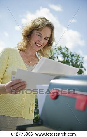 Stock Photograph - USA, New Jersey, Jersey City, Woman checking mail at mailbox. Fotosearch