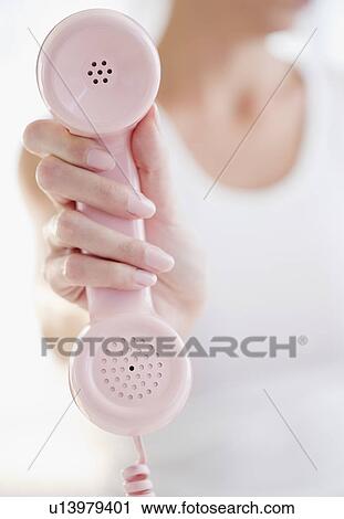 Stock Image - USA, New Jersey, Jersey City, Woman's hand holding pink telephone receiver. Fotosearch