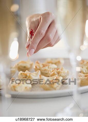 Stock Photo - USA, New Jersey, Jersey City, Woman's hand sticking toothpick into fresh snack. Fotosearch