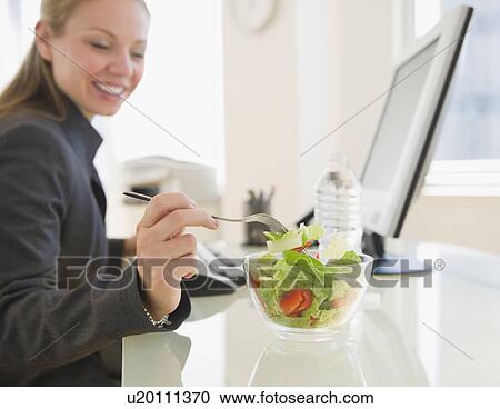 USA, New Jersey, Jersey City, young businesswoman eating salad in office View Large Photo Image Stock Image - USA, New Jersey, Jersey City, young businesswoman eating salad in office. Fotosearch
