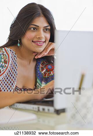 Stock Image - USA, New Jersey, Jersey City, Young Indian woman using laptop. Fotosearch