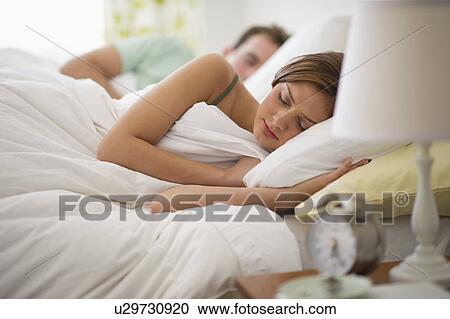 Stock Image - USA, New Jersey, Jersey City, Young couple sleeping in bed. Fotosearch
