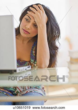 Stock Photo - USA, New Jersey, Jersey City, Young Indian woman using laptop. Fotosearch