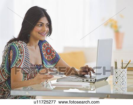 Stock Photo - USA, New Jersey, Jersey City, Young Indian woman using laptop. Fotosearch