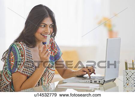 Stock Photo - USA, New Jersey, Jersey City, Young Indian woman using laptop. Fotosearch