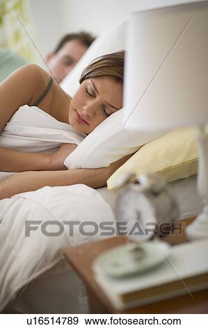 Stock Photo - USA, New Jersey, Jersey City, Young couple sleeping in bed. Fotosearch
