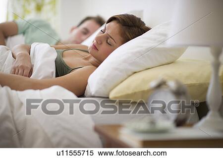 Stock Photography - USA, New Jersey, Jersey City, Young couple sleeping in bed. Fotosearch