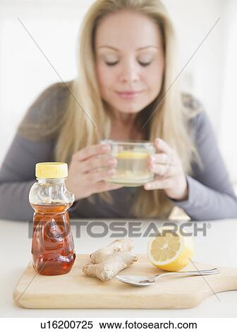 USA, New Jersey, Jersey City, Young woman drinking tea with ginger and lemon View Large Photo Image Stock Photography - USA, New Jersey, Jersey City, Young woman drinking tea with ginger and lemon. Fotosearch