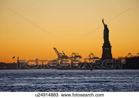 Stock Image - USA, New York City, Staten Island, Harbor and silhouette of Statue of Liberty in background. Fotosearch