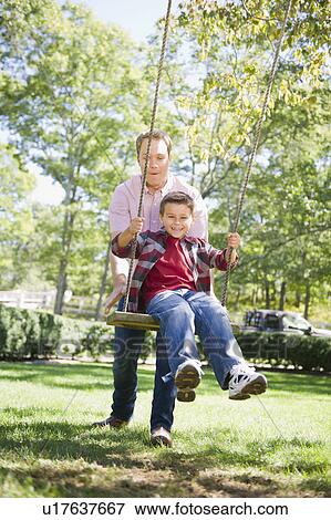 Stock Photo - USA, New York, Flanders, Father and son (8-9) playing in garden. Fotosearch