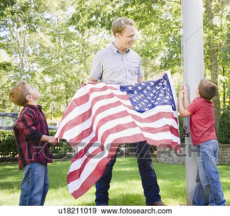 Stock Photo - USA, New York, Flanders, Father with two boys (4-5, 8-9) hanging American flag on pole. Fotosearch