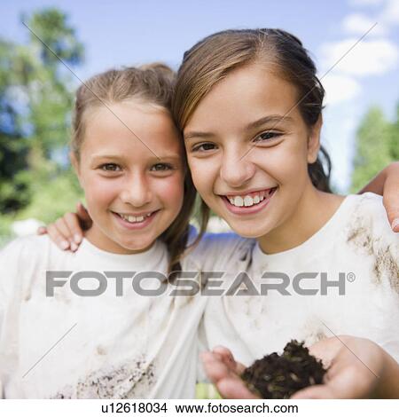 USA, New York, Two girls (10-11, 10-11) holding soil wearing dirty t-shirts View Large Photo Image Picture - USA, New York, Two girls (10-11, 10-11) holding soil wearing dirty t-shirts. Fotosearch