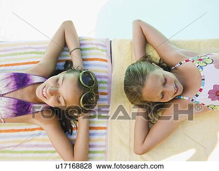 Stock Photo - USA, New York, Two girls (10-11, 10-11) lying on towels. Fotosearch