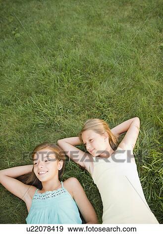 USA, New York, Two girls (10-11, 10-11) lying on grass backyard View Large Photo Image Stock Photo - USA, New York, Two girls (10-11, 10-11) lying on grass backyard. Fotosearch