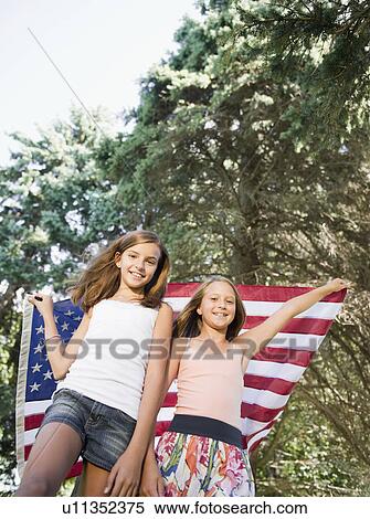 Stock Photography - USA, New York, Two girls (10-11, 10-11) playing with American flag. Fotosearch