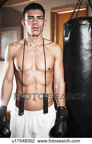 Stock Image - USA, Seattle, Portrait of young man in gym wearing boxing gloves. Fotosearch