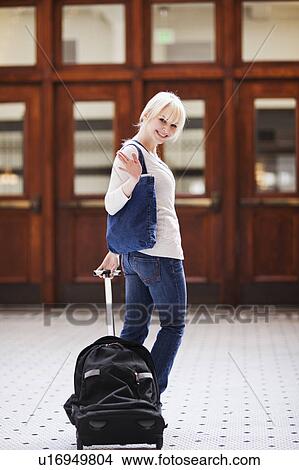 Picture - USA, Seattle, Young woman at train station standing with luggage and looking at camera. Fotosearch