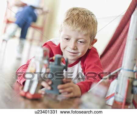 Stock Image - USA, Utah, Boy (6-7) playing on floor. Fotosearch