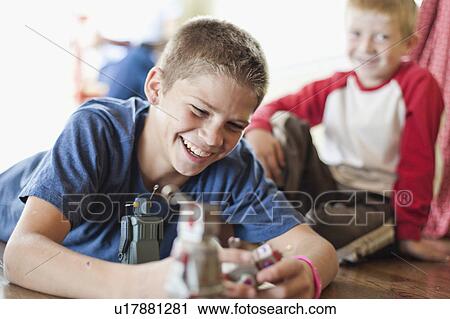 Stock Image - USA, Utah, Boys (6-7, 12-13) playing on floor. Fotosearch
