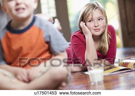 Stock Image - USA, Utah, Children (4-11) relaxing in home, girl reading book. Fotosearch