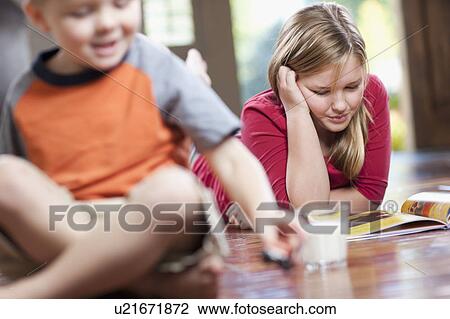 Stock Image - USA, Utah, Children (4-11) relaxing in home, girl reading book. Fotosearch