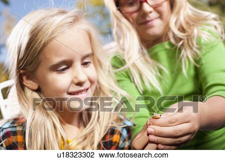 Stock Image - USA, Utah, close up of sisters (6-7, 8-9 ) holding frog. Fotosearch