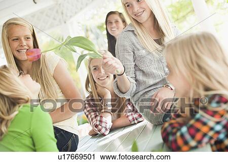 Stock Image - USA, Utah, family portrait of sisters (6-7, 8-9, 12-13, 14-15, 16-17) at table playing with flower. Fotosearch