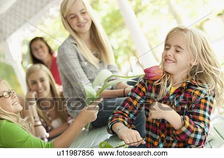 Stock Photograph - USA, Utah, family portrait of sisters (6-7, 8-9, 12-13, 14-15, 16-17) at table playing with flower. Fotosearch